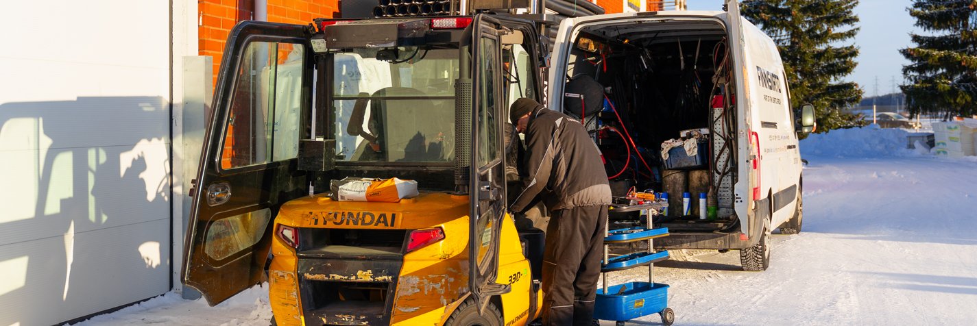 Finnsiirron huoltoauto ja trukkimekaanikko töissä teollisuushallin pihalla