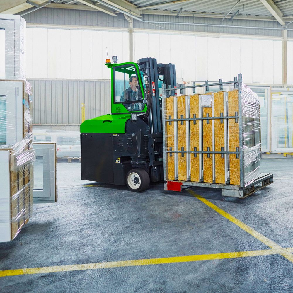Combilift monitievastapainotrukki käsittelee ikkunaelementtejä varastossa